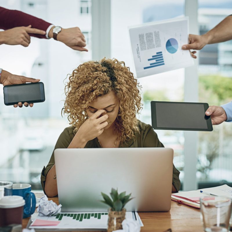 Shot of a young businesswoman looking stressed out in a demanding office environment.